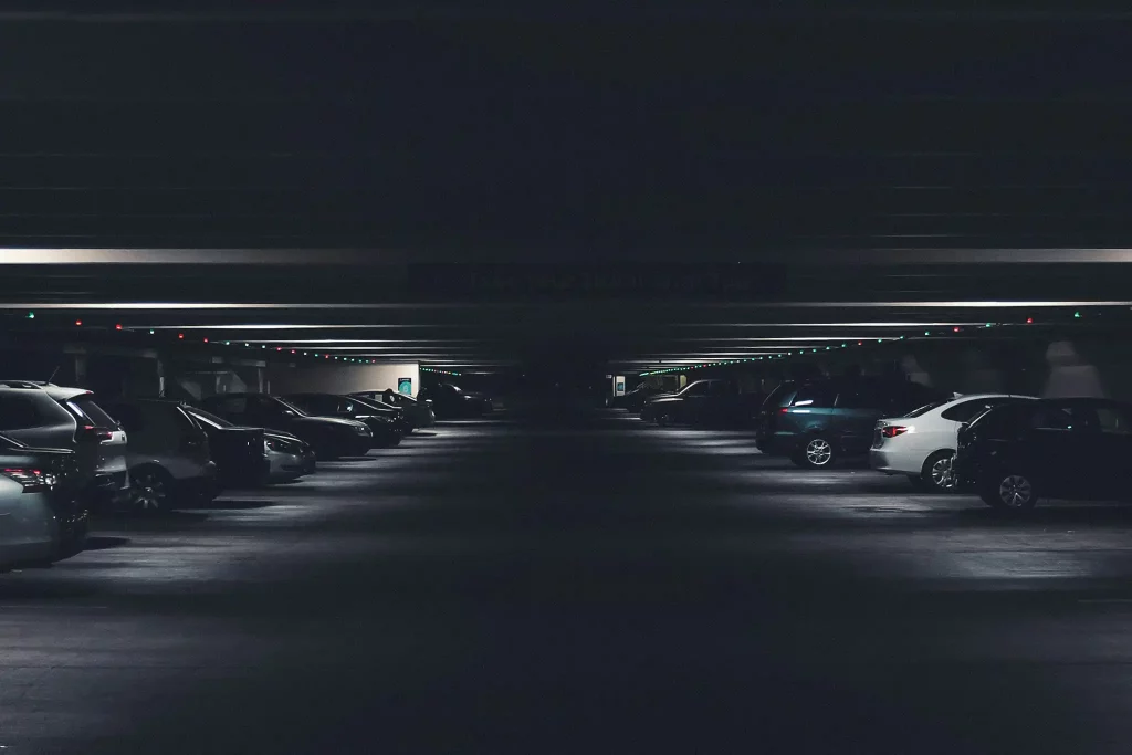 Parking souterrain sombre avec voitures garées et éclairage directionnel au plafond